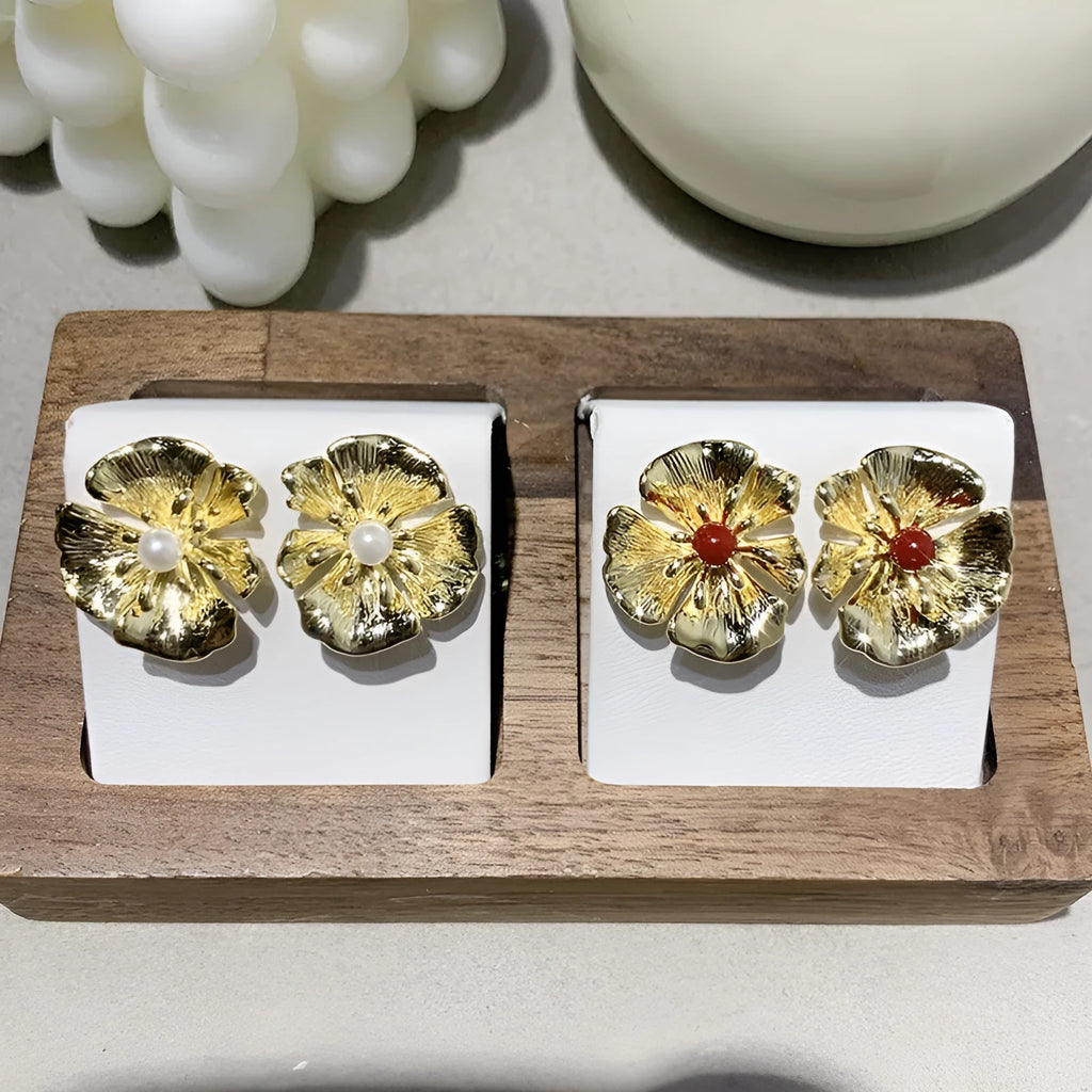 Pearl flower shaped metal earrings in red and white colour options on a grey background