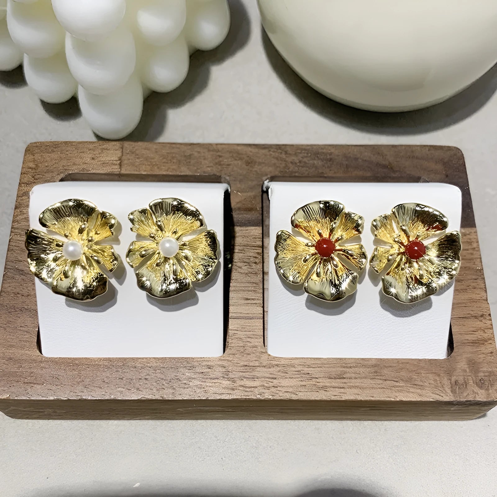 Pearl flower shaped metal earrings in red and white colour options on a grey background