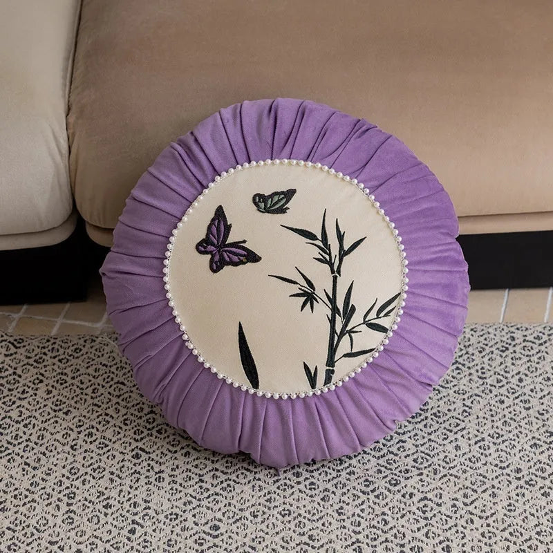 Square decorative cushion with Chinese butterfly embroidery in beige, black, and purple threads.