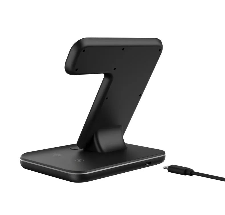 White three-in-one wireless charging stand holding a mobile phone, a smartwatch, and wireless earbuds on a desk.