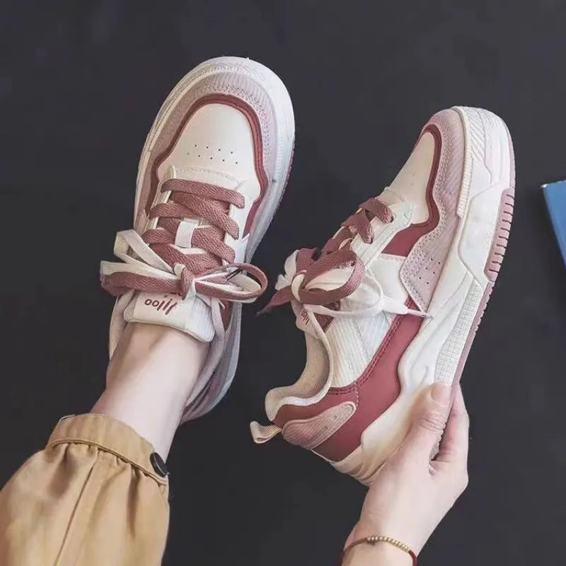 Women's pink and white low-top sneakers with a height-increasing rubber sole on a neutral background.