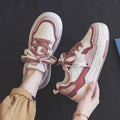 Women's pink and white low-top sneakers with a height-increasing rubber sole on a neutral background.