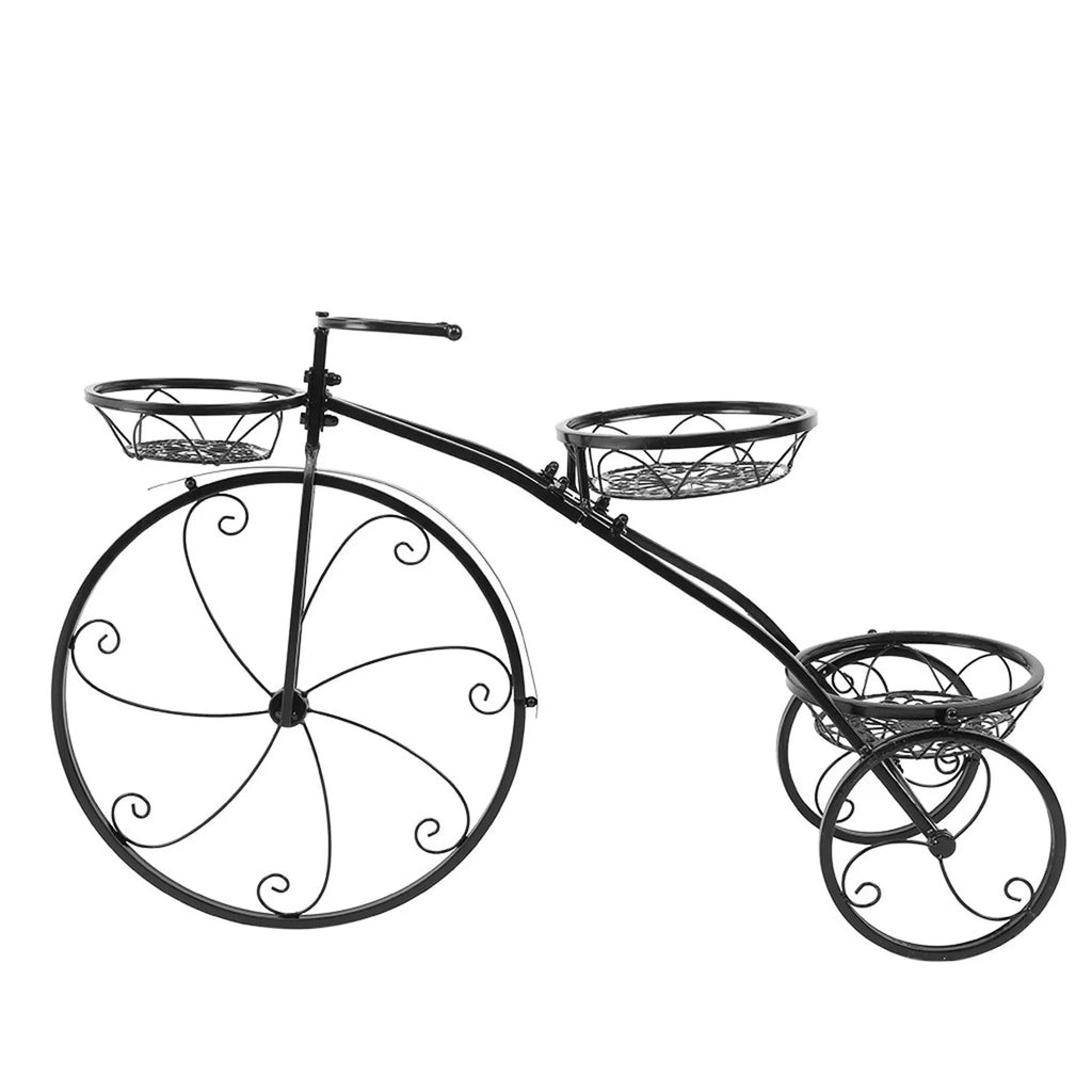 Black wrought iron tricycle plant stand with three round baskets holding small potted plants on a patio