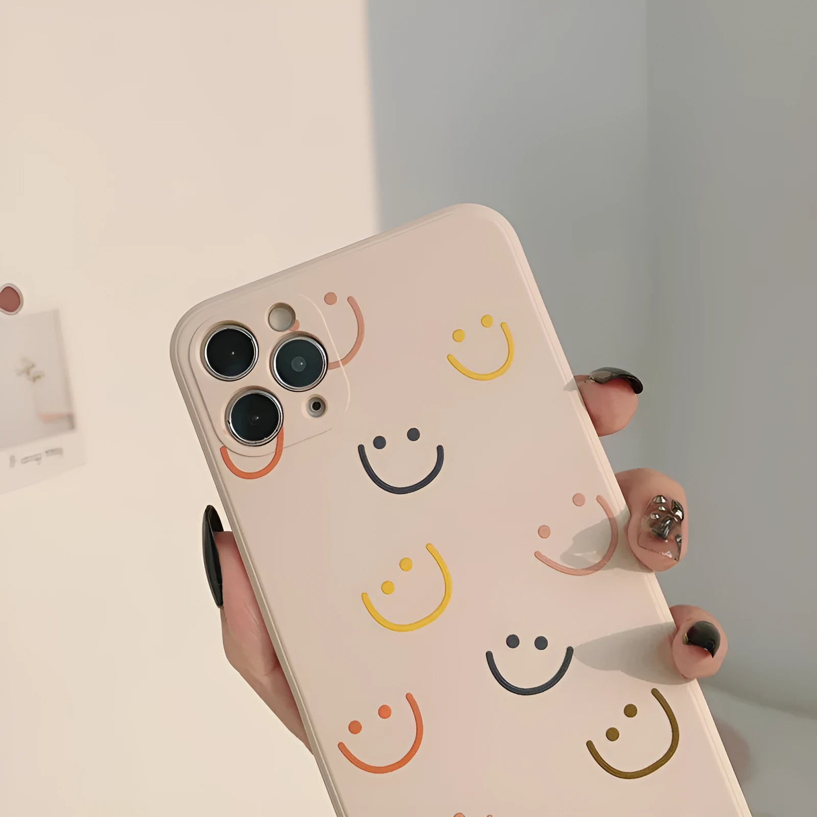 Simple TPU silicone iPhone case with painted smiley face and graffiti design on a table
