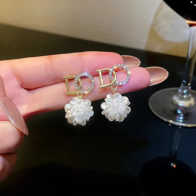 White acrylic DO letter embroidered ball stud earrings for women on light background