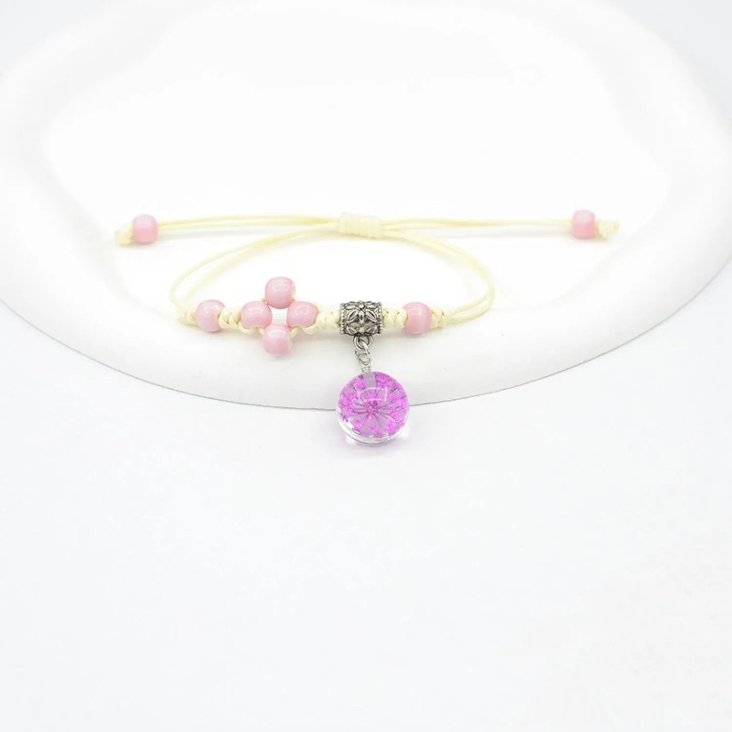 Close-up of a hand-woven glass bracelet with large 1.4cm beads containing real dried flowers in various colours.