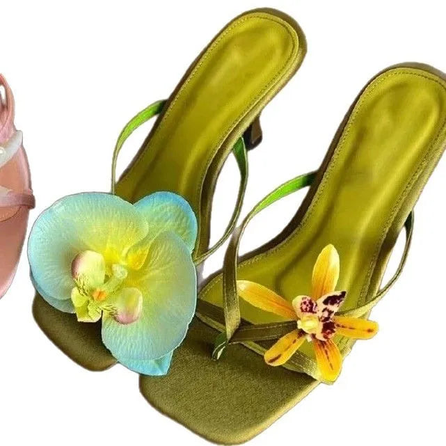 Women's black asymmetric floral high-heel sandals with a square toe and calf leather upper.