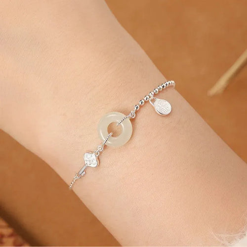 Women's silver bracelet with a geometric Hetian jade Wishful Blessings charm on a white background.