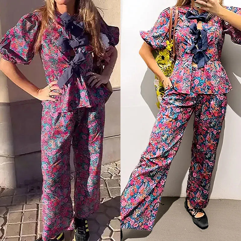 Women's floral print polyester trouser suit with tie-neck top and puff sleeves.
