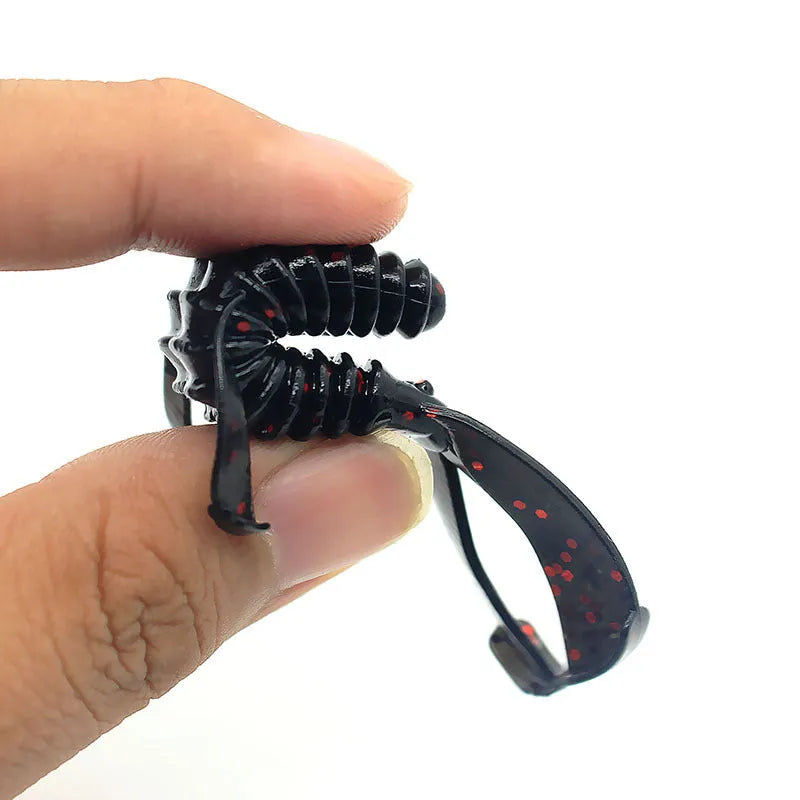 PVC soft plastic fishing lure in a worm shape, shown in a selection of different colours on a tackle box.