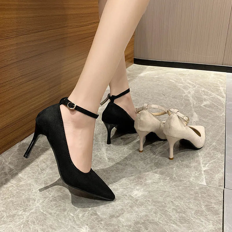 Women's black and creamy white stiletto heel pumps with a buckle fastening.