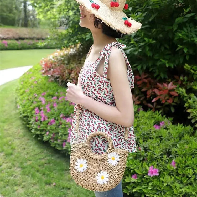 Light brown straw weave crossbody bag with daisy accents and adjustable strap