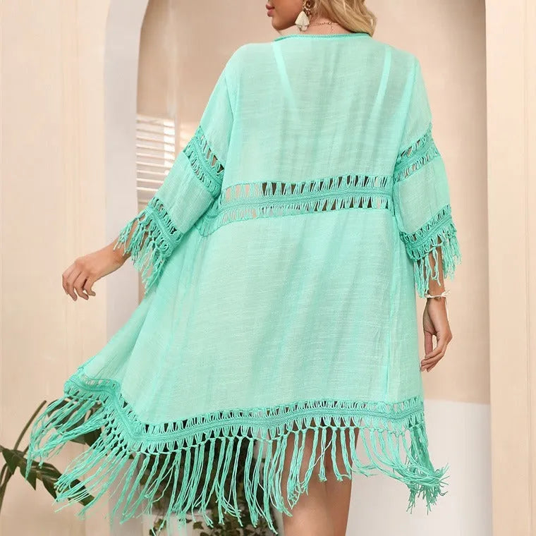 Yellow hand-crocheted women's beach cardigan with tassel trim on a hanger.