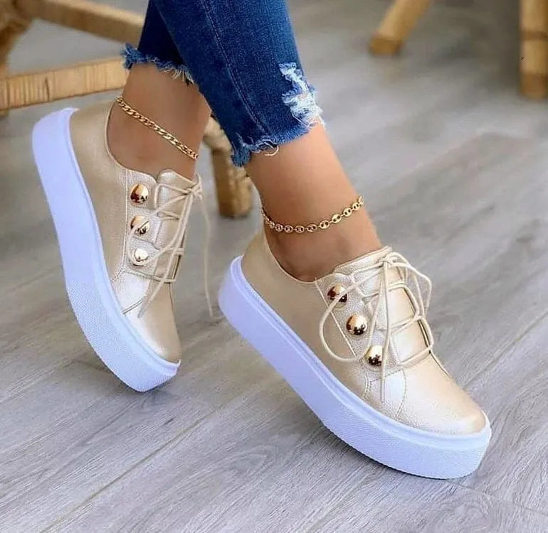 Women's white lace-up flats sneakers with round toe and silver rivet details on the low upper.