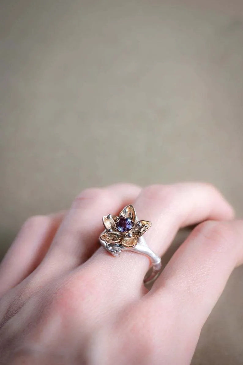Silver two-tone women's ring with a geometric shape and floral design details on a plain background.