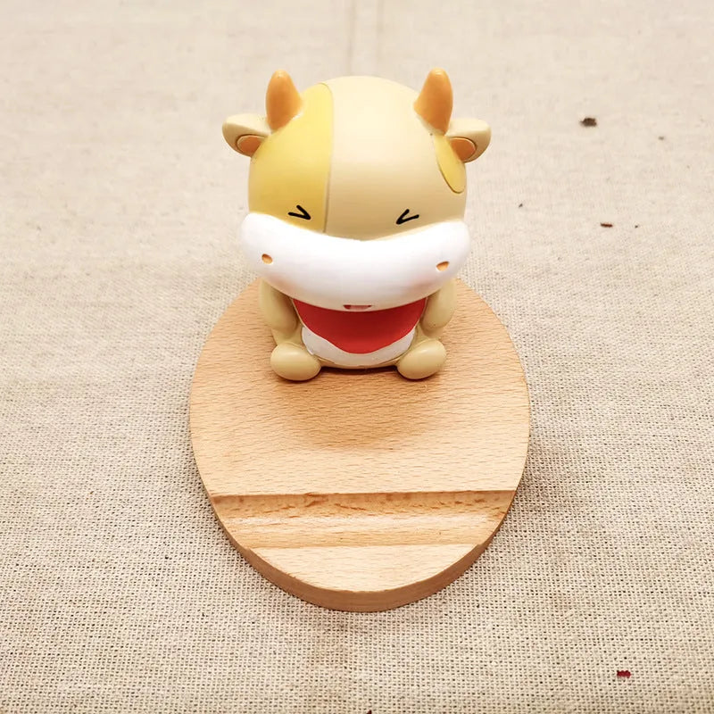 Beech wood and resin lazy bracket mobile phone holder in an animal design style on a desk.