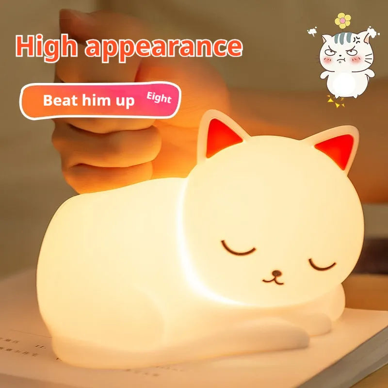 Sleepy cat silicone night light with warm white glow, induction pat feature, on a bedside table