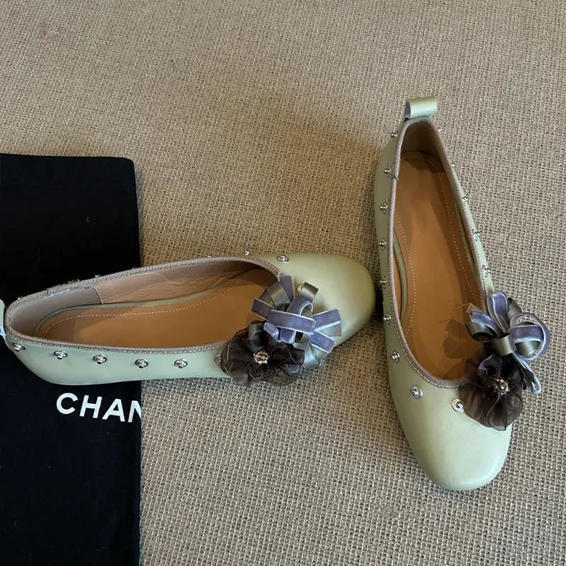 Women's silver Mary Jane flat shoes with flower rivets and a buckle strap on a sheepskin upper.