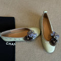 Women's silver Mary Jane flat shoes with flower rivets and a buckle strap on a sheepskin upper.