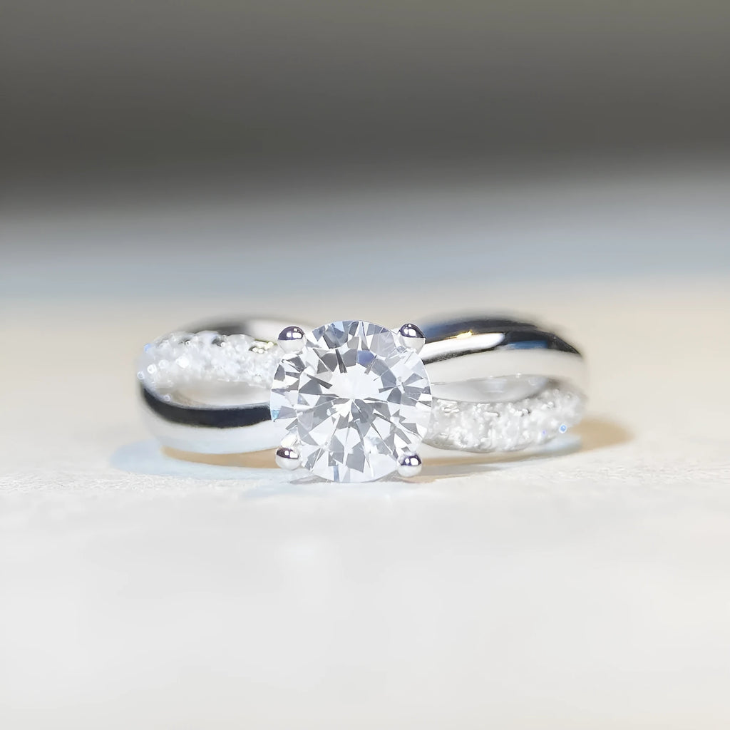 Silver geometric cross ring with a 1-karat moissanite stone on a twisted band.
