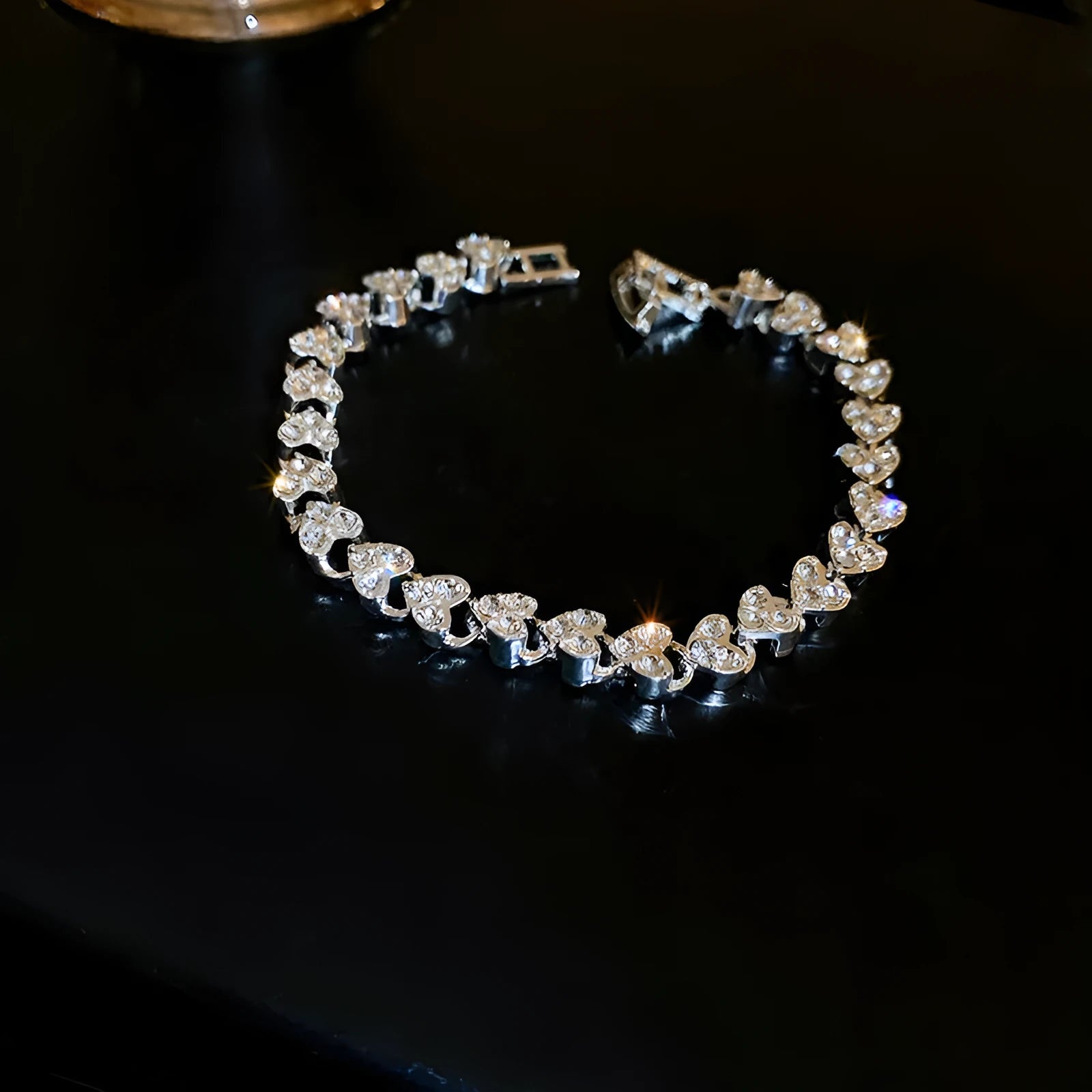 Silver metal heart-shaped bracelet with inlaid zircon on a plain background