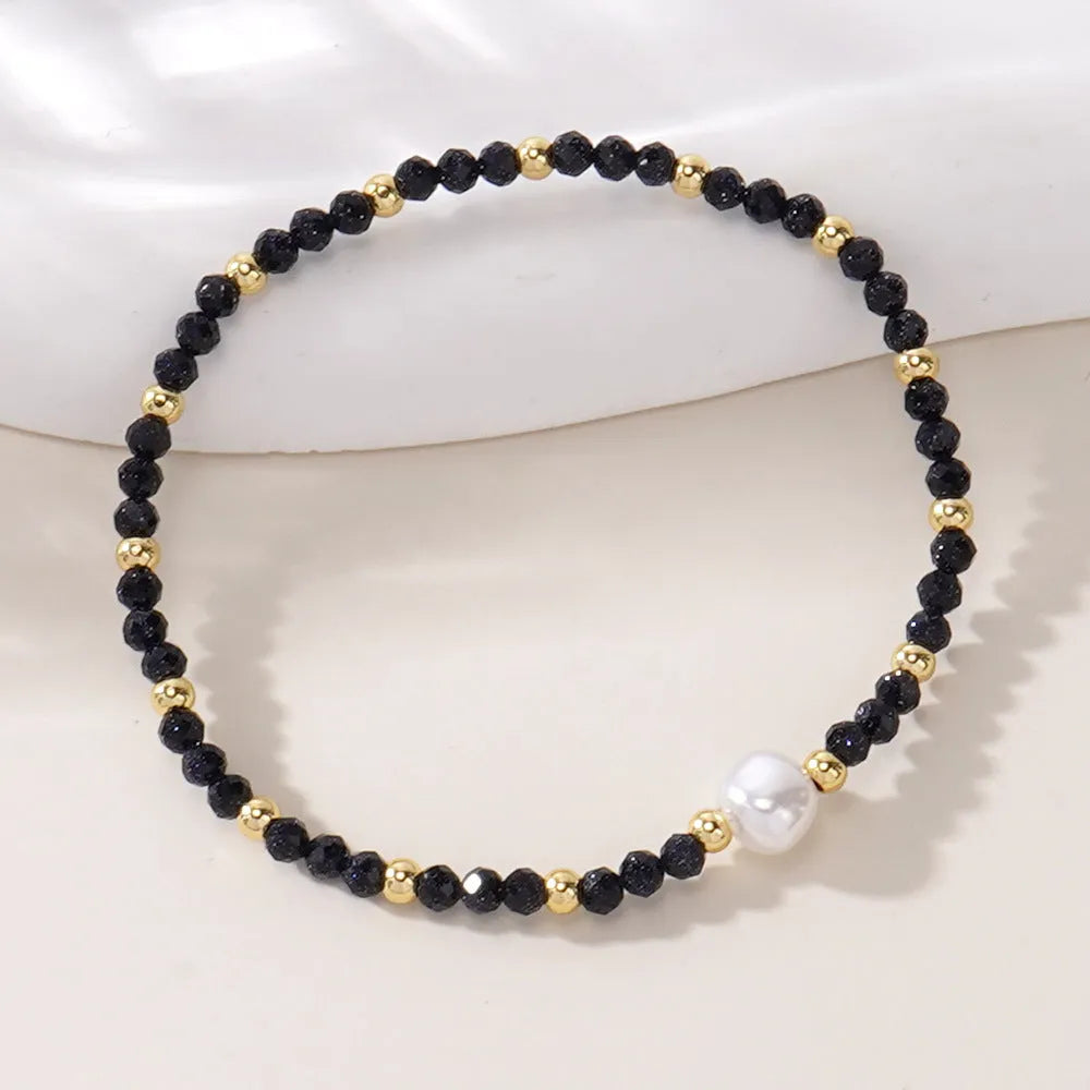 Close-up of a unisex natural stone bracelet with geometric ellipse beads on a wrist.
