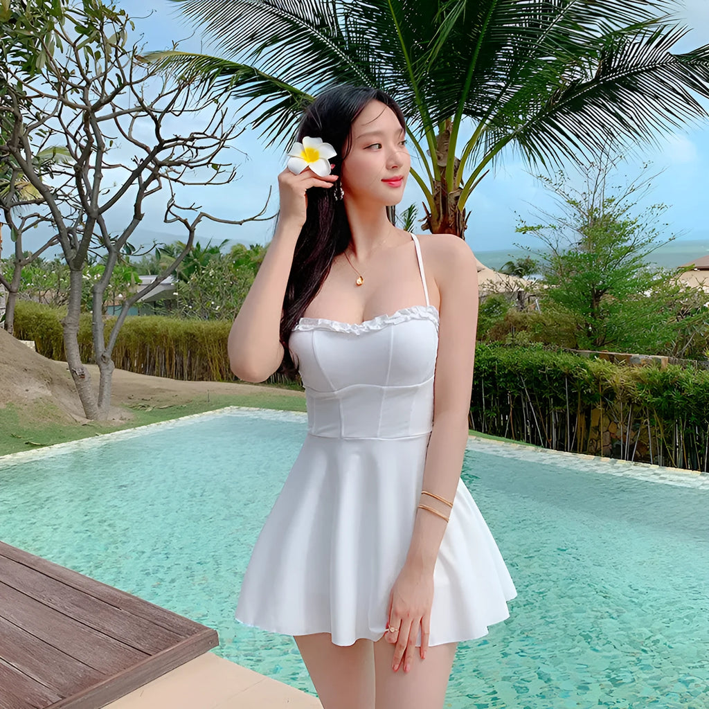 White women's one-piece swimsuit with hollow out pattern and skirted bottom.