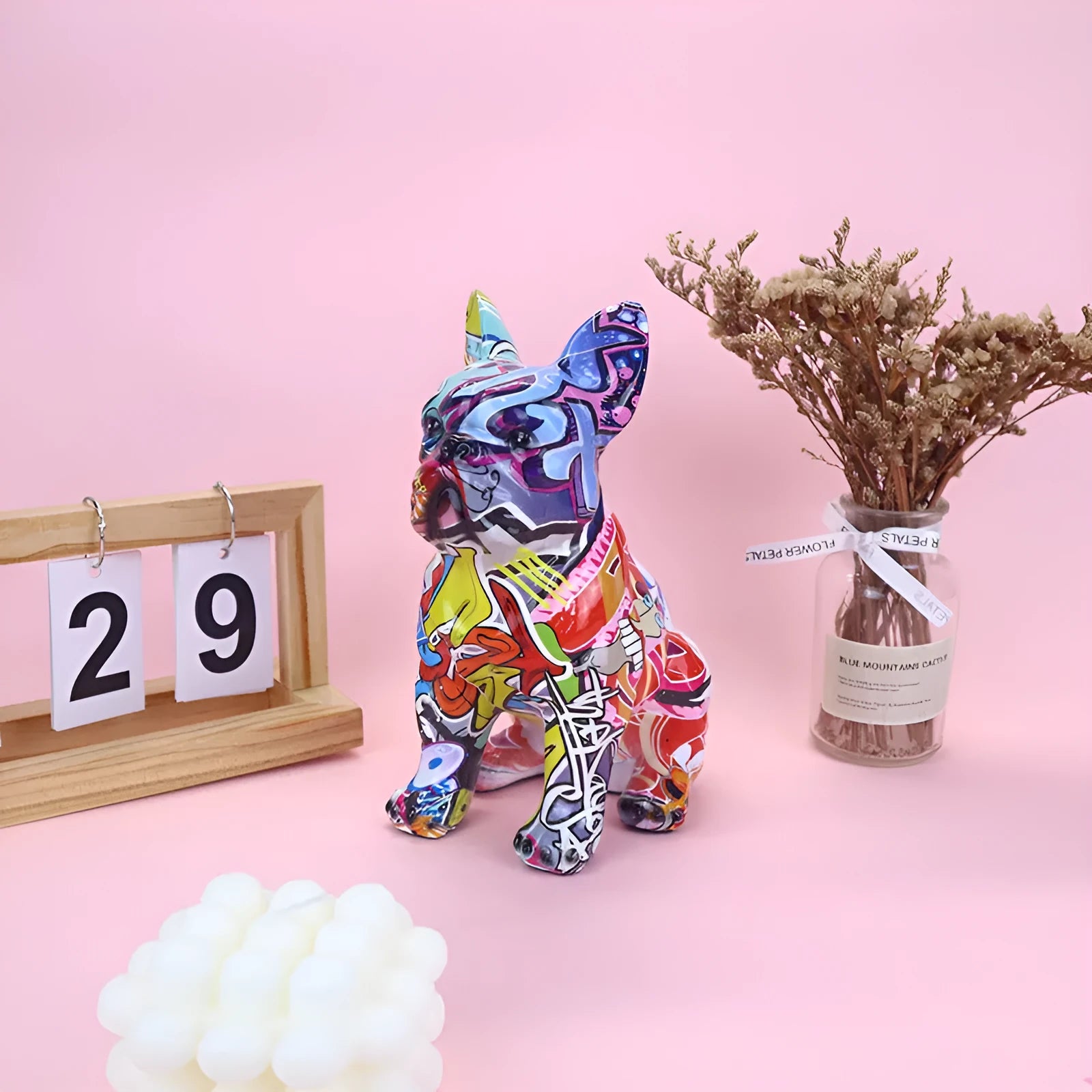 Graffiti-coloured resin French bulldog statue on a plain background.