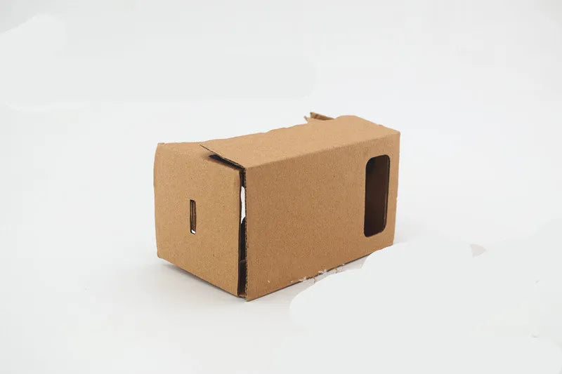 Pink and white foldable VR cardboard glasses for mobile phones, showing 3D lenses and rubber band.