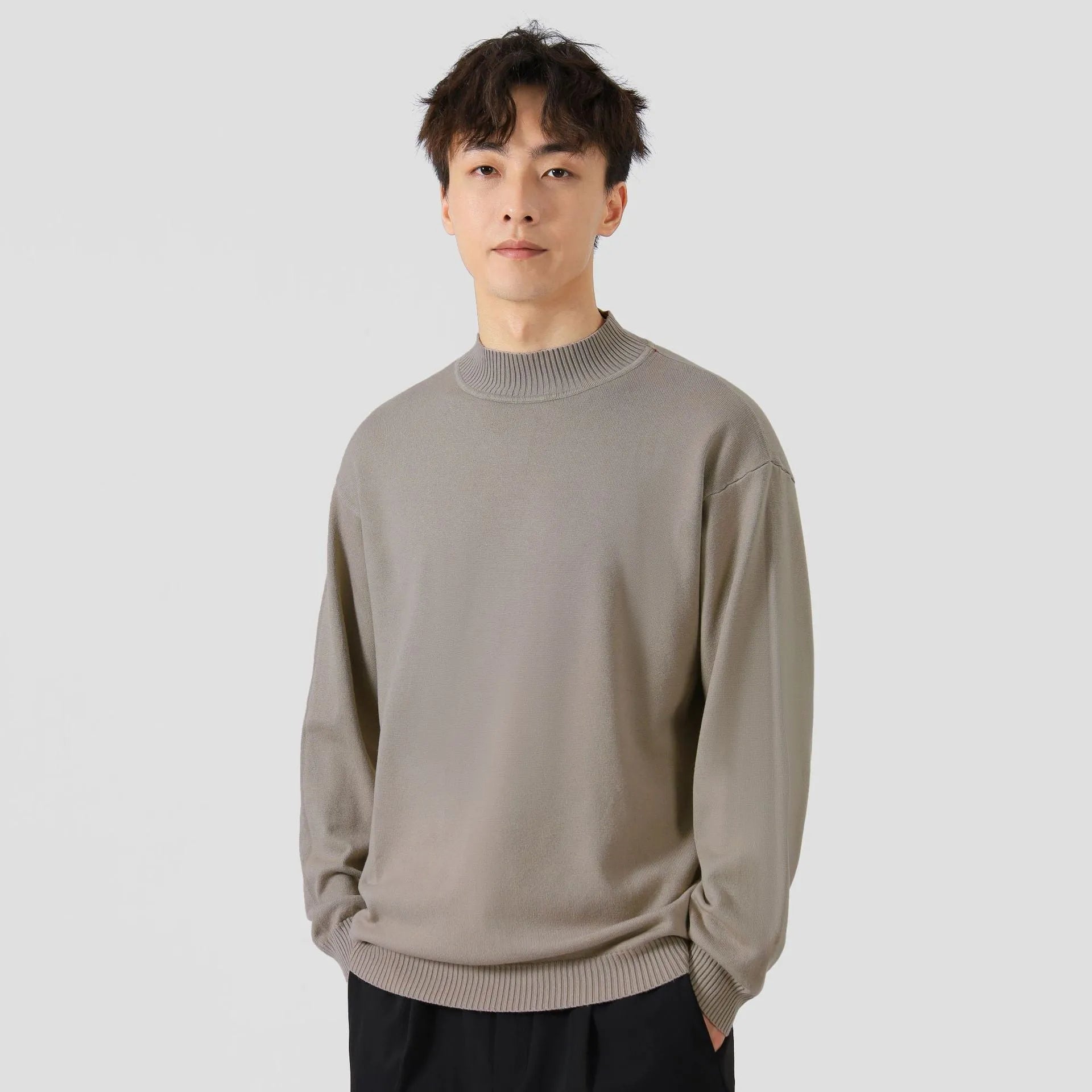 A man's loose-fitting, long-sleeve pullover sweater in a solid colour, showing a casual relaxed fit.