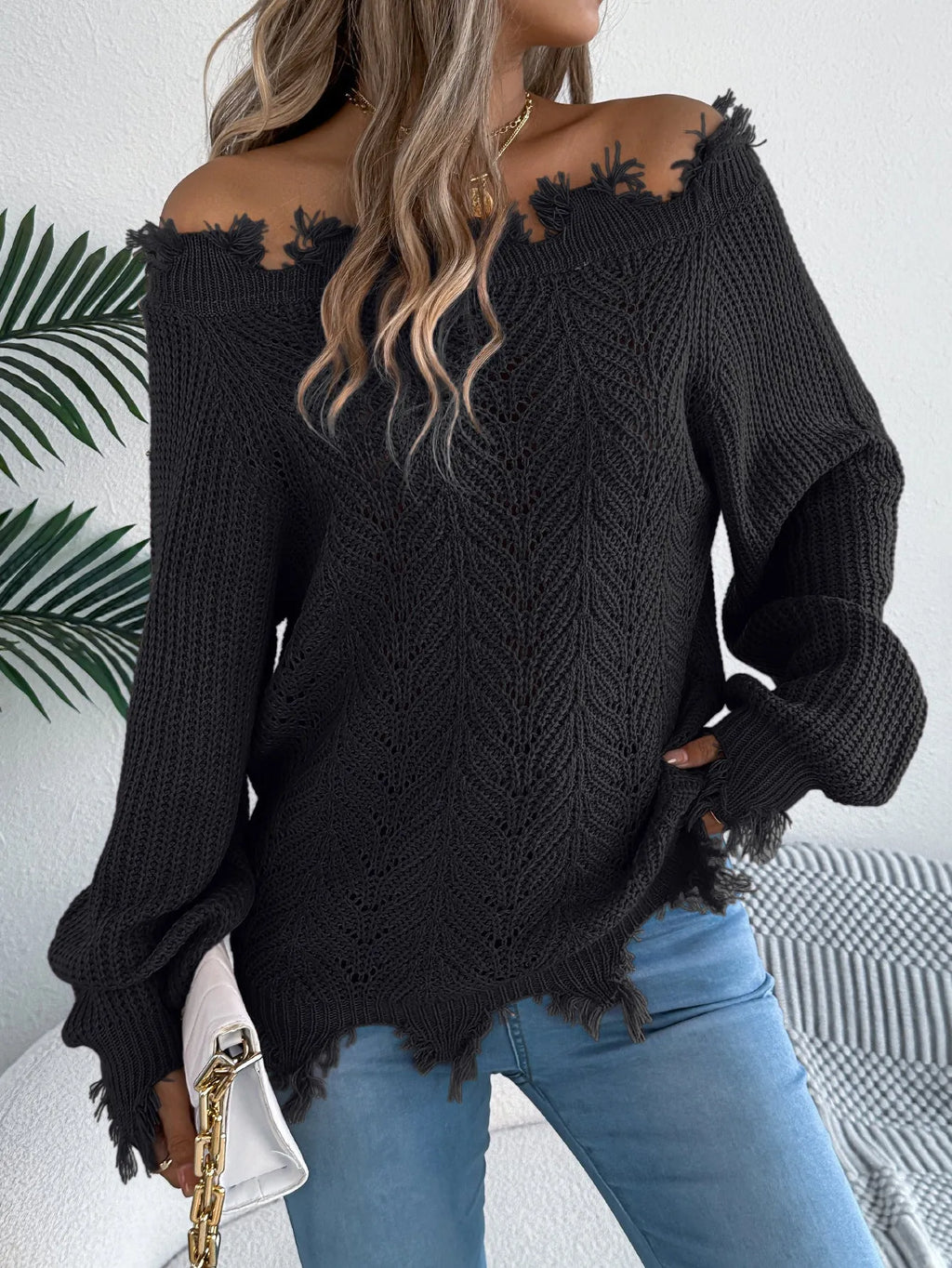 White cut-off-shoulder pullover sweater with hollow-out long sleeves on a mannequin.