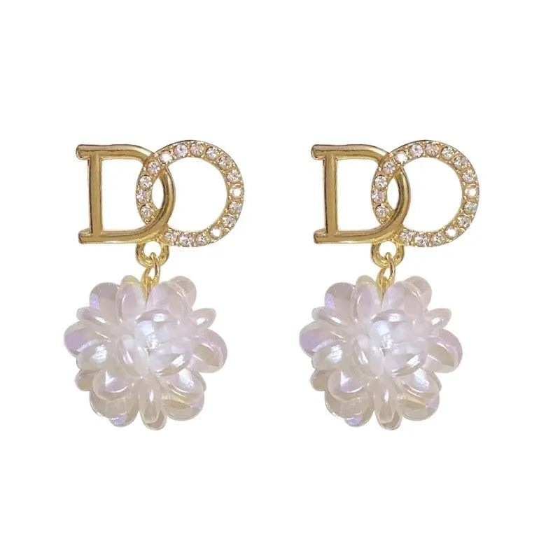 White acrylic DO letter embroidered ball stud earrings for women on light background