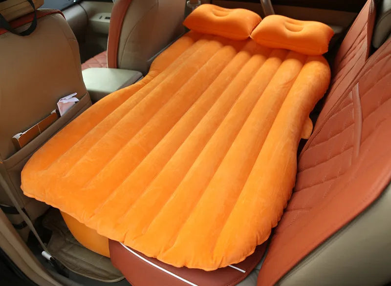 Inflatable car bed with flocked surface folded beside two pillows in storage bag for vehicle sleeping