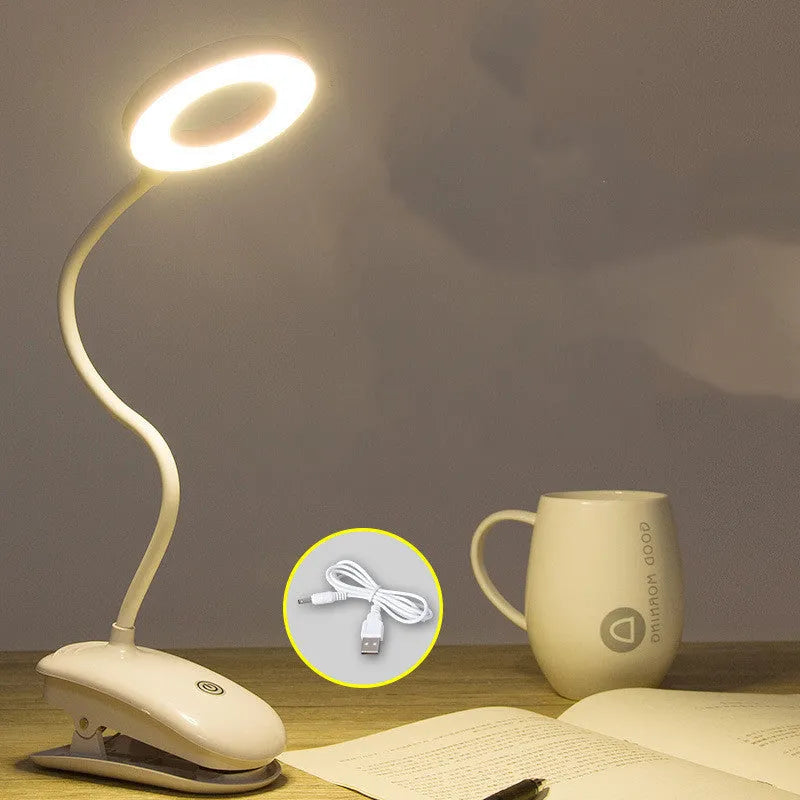 Modern clip-on rechargeable desk lamp with a white plastic shade and touch controls on its base.