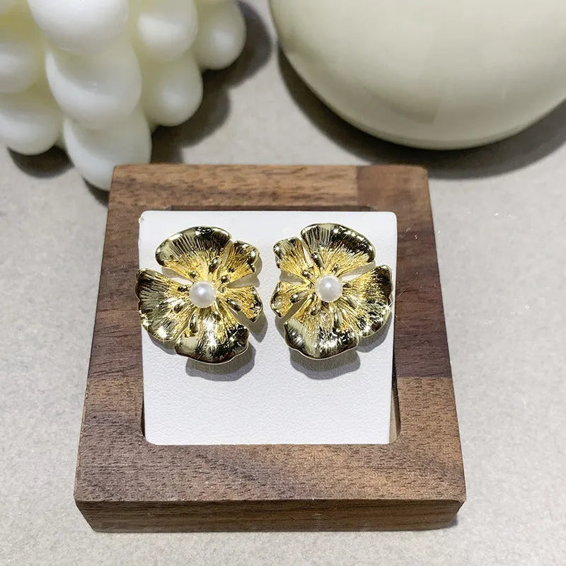 Pearl flower shaped metal earrings in red and white colour options on a grey background