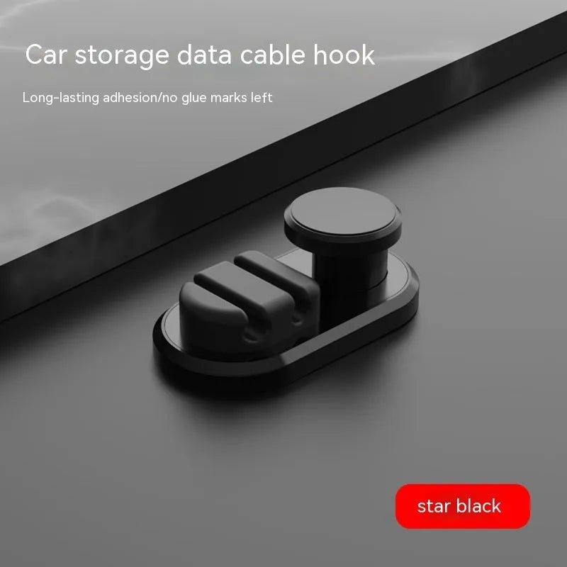 Dark green ABS silicone car cable hook with adhesive backing for organising data cables on a dashboard.
