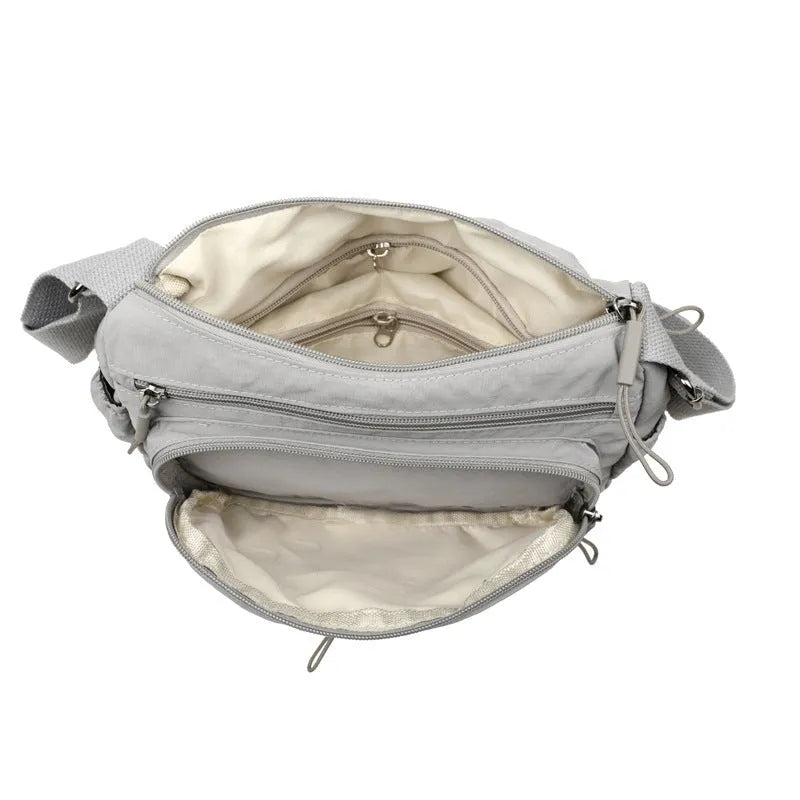 Grey water-repellent nylon crossbody bag showing outer pocket and internal organiser compartments.
