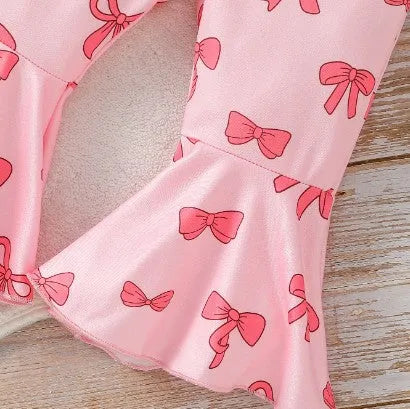 Pink two-piece girls' suit with long sleeve flounced sleeve knitted sweater, printed bow, and flared pants on white background