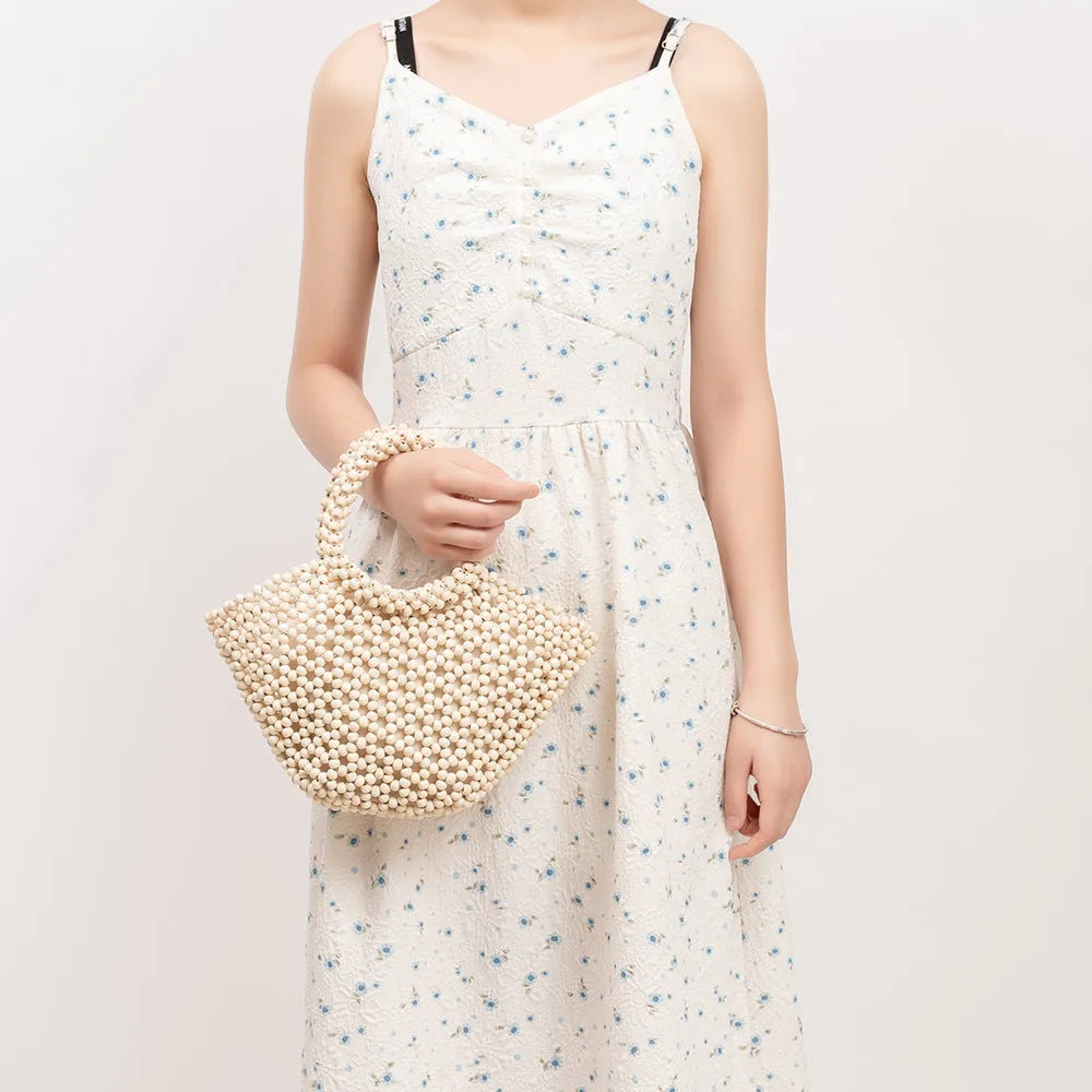 Hand-woven dumpling-shaped handbag with wooden beads in milky white colour
