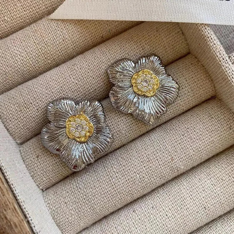 Close-up of women's copper stud earrings with a textured floral design in a two-tone colour.