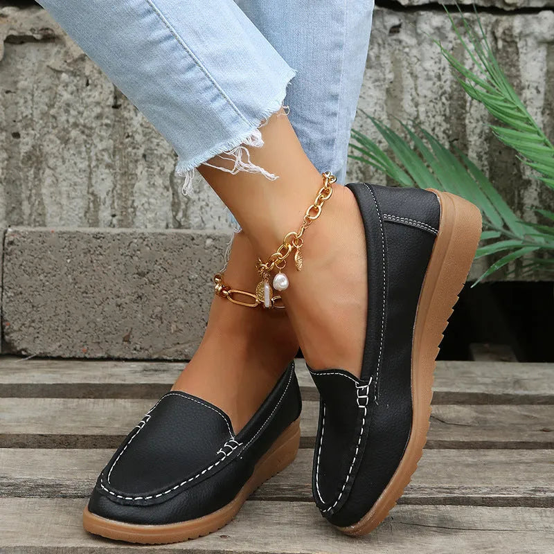 Women's black PU leather flat loafers with round toe and car suture design on a rubber sole.
