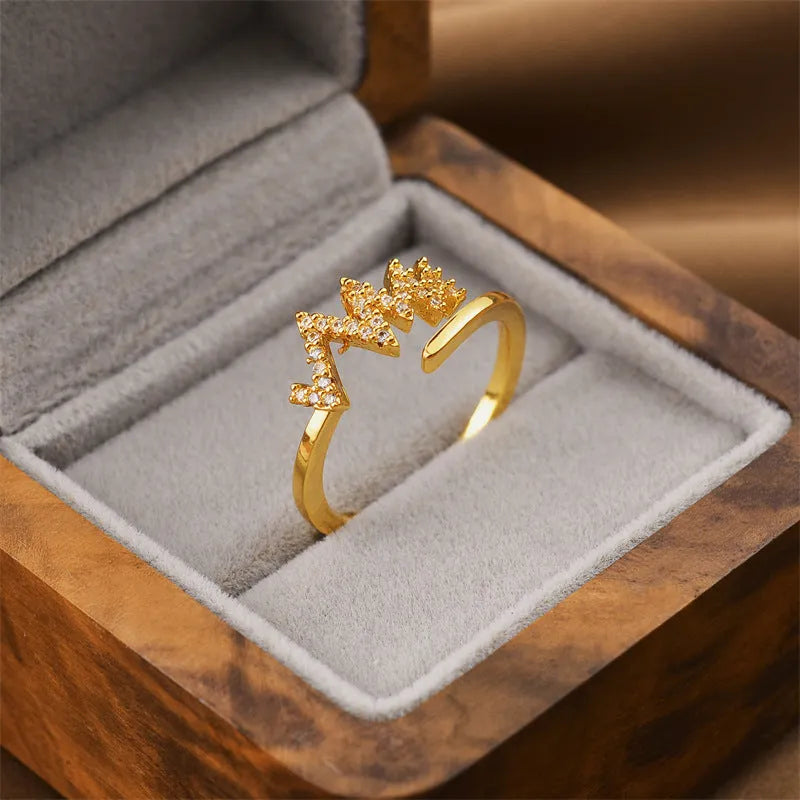 Gold electroplated geometric women's ring with an open adjustable design on a plain background