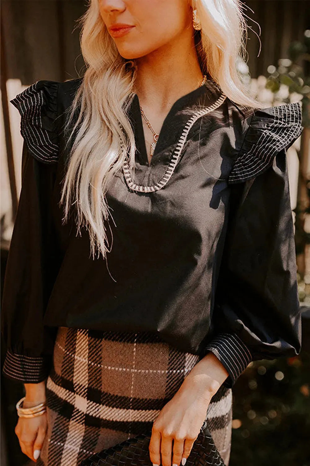Black V-neck long sleeve blouse with ruffle trim and contrast stitching.