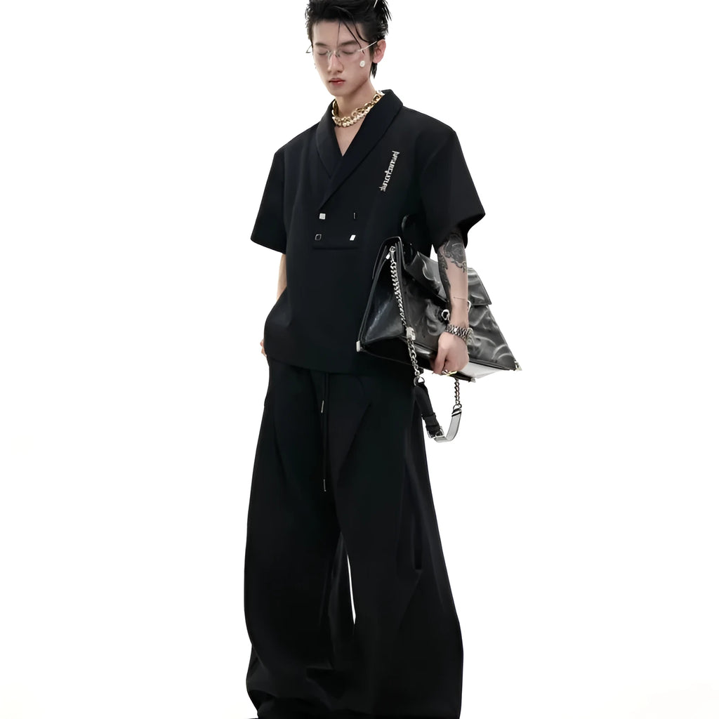 Men's dark grey cotton sports suit with V-neck top featuring padded shoulders and metal embellishments, paired with matching shorts.