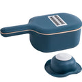 Dark blue vegetable cutter with four stainless steel blades, a drain basket, and a hand guard on a kitchen counter.