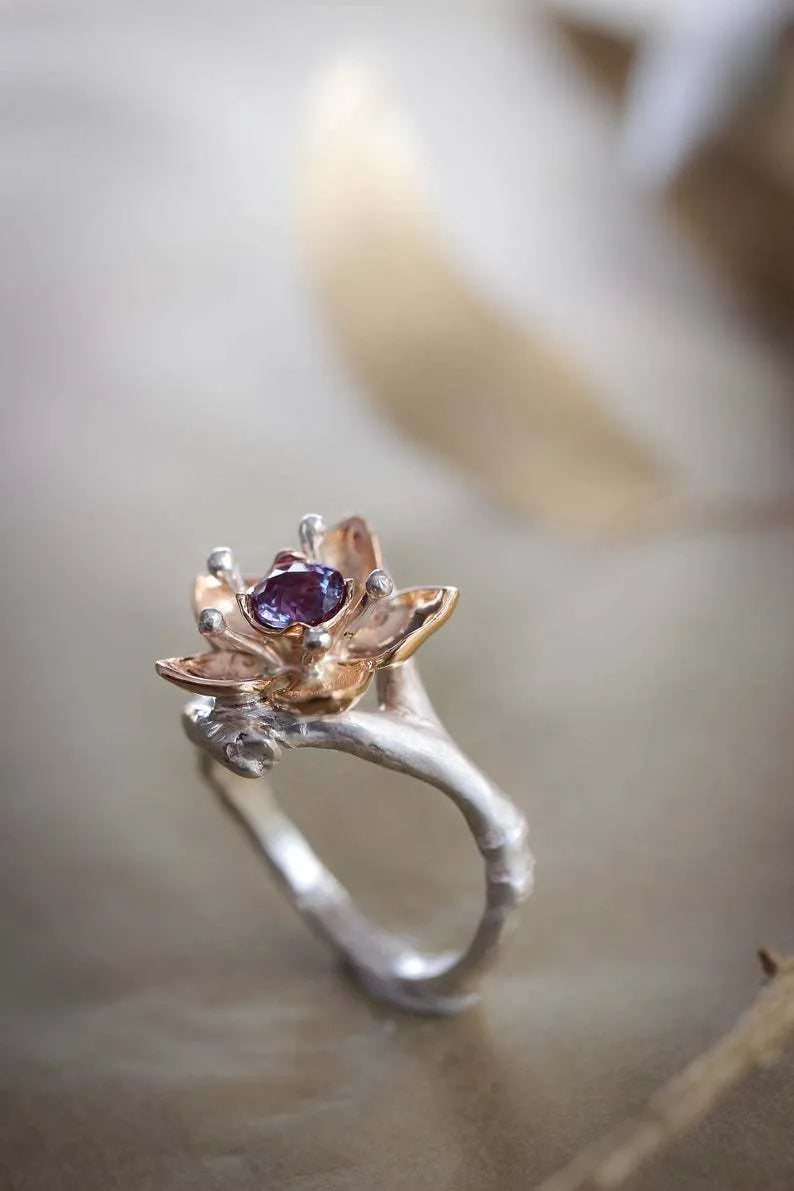 Silver two-tone women's ring with a geometric shape and floral design details on a plain background.