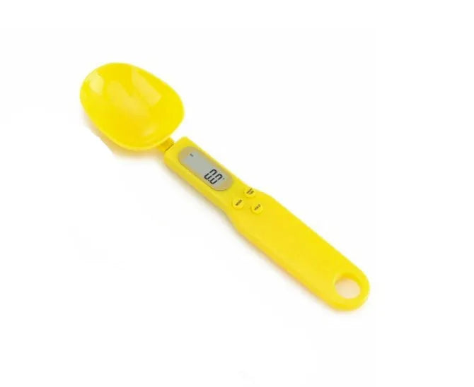White digital kitchen scale with LCD screen displaying weight, shown next to a measuring spoon.