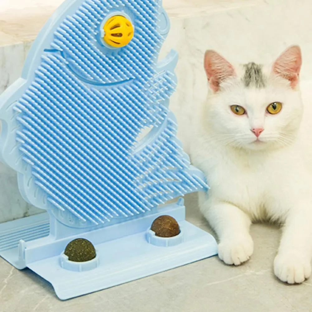 Blue plastic fish-shaped cat wall scratcher with brush, two green catnip balls, a bell, and a mounting base.
