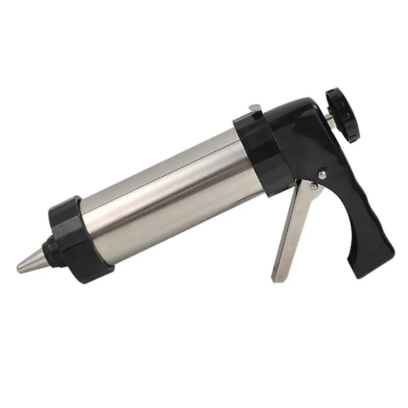Stainless steel biscuit press gun with assorted cookie mould discs and icing nozzles on a baking tray.