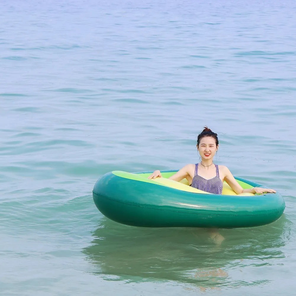 Large green inflatable avocado pool float on blue water.